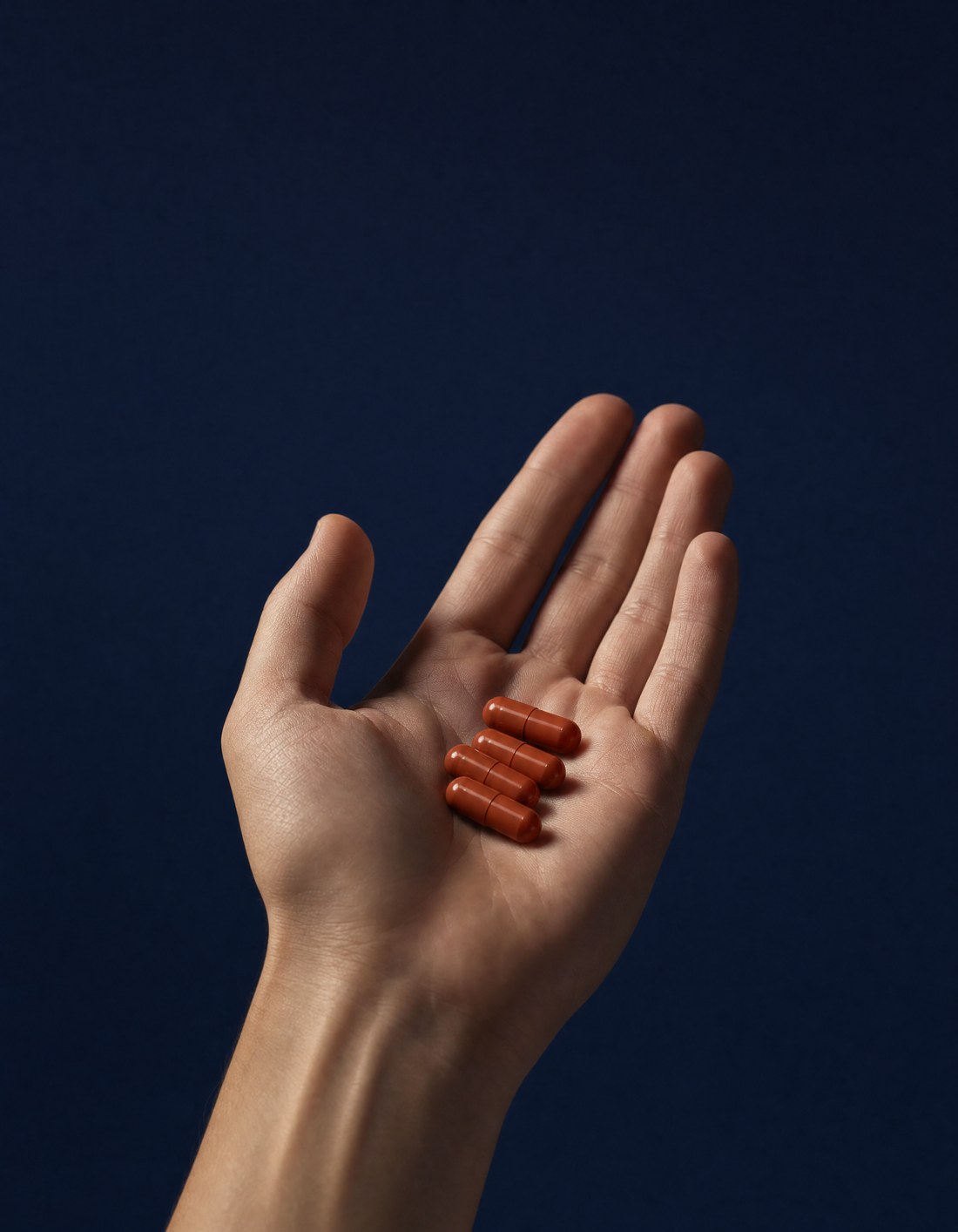 Mano che tiene quattro capsule AlphaPeak T1x, la formula quotidiana per l'uomo